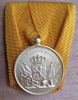 Zilveren medaille.
Onderscheidingsteken voor langdurige, eerlijke en trouwe dienst.
